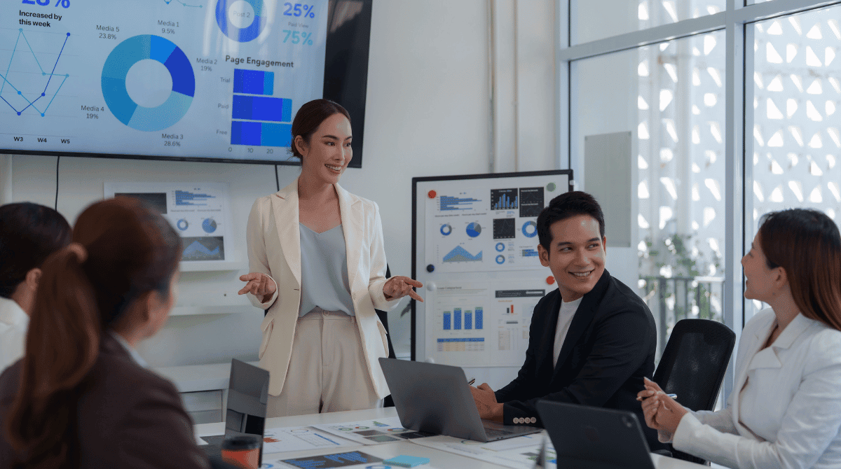 A business woma presents an analytics dashboard, showcasing how data-driven insights form the foundation of Strategic Intelligence & Enablement.
